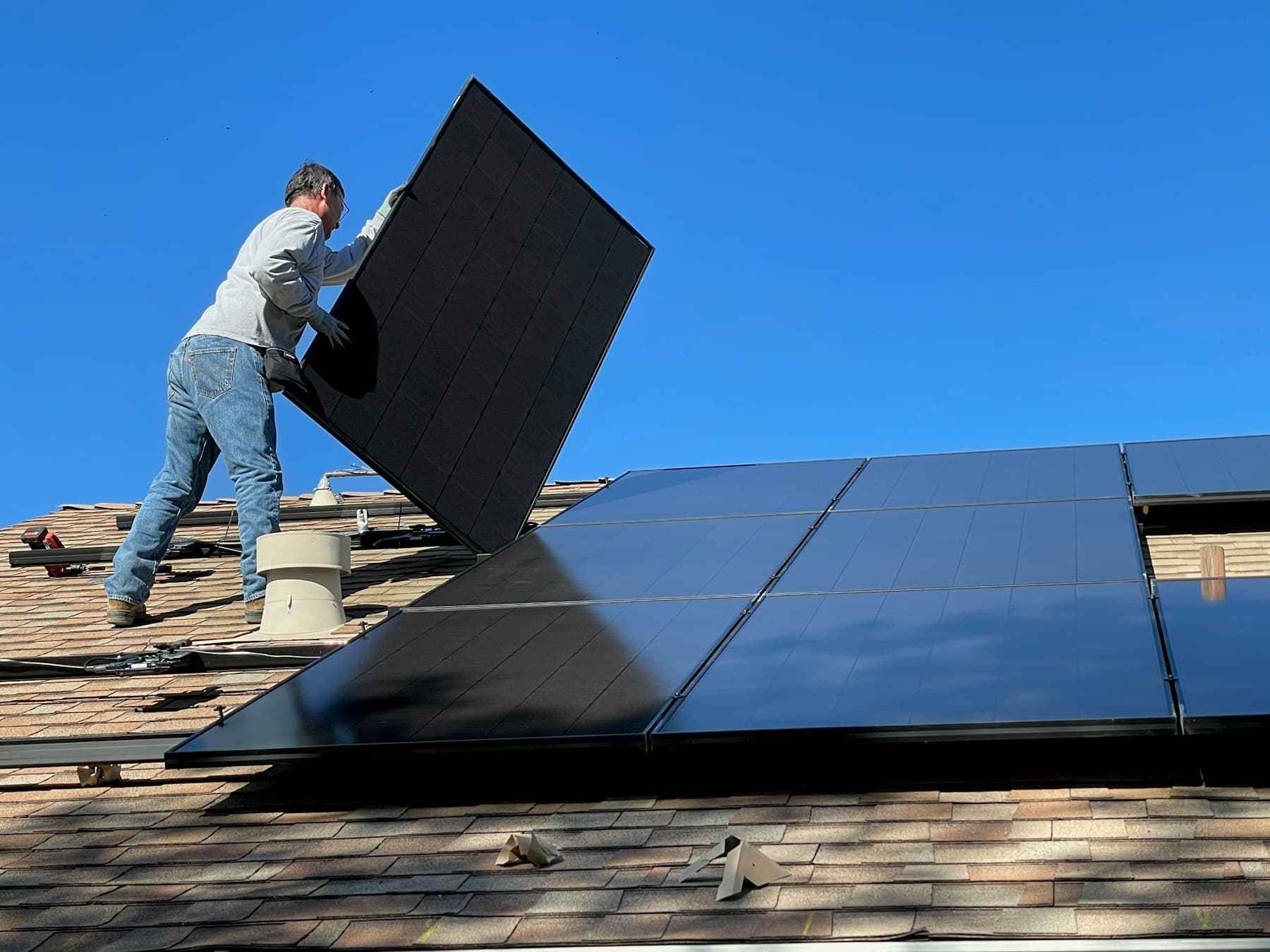 Installer fitting a solar module on a residential roof
